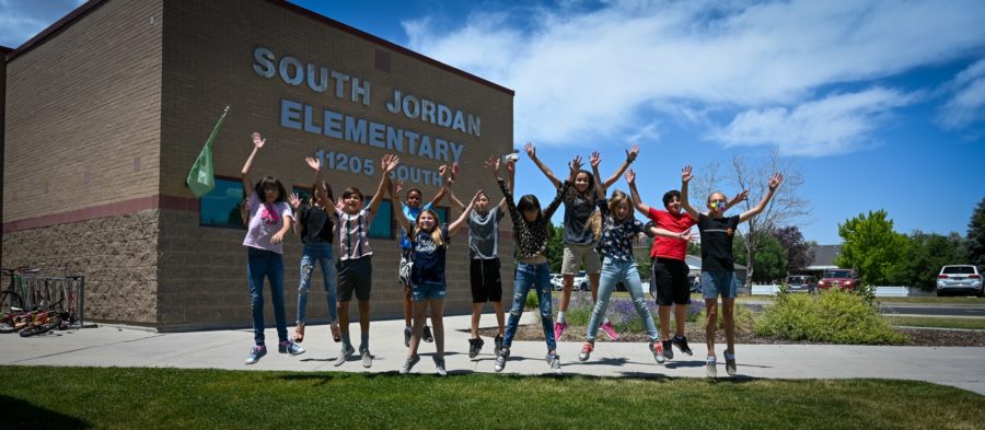 Photo of elementary students jumping and waving hello.